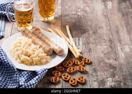 Bratwurst, Sauerkraut, Brezeln und Bier auf Holztisch Stockfoto