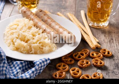 Bratwurst, Sauerkraut, Brezeln und Bier auf Holztisch Stockfoto