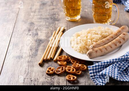 Bratwurst, Sauerkraut, Brezeln und Bier auf Holztisch Stockfoto