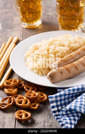 Bratwurst, Sauerkraut, Brezeln und Bier auf Holztisch Stockfoto