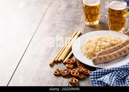 Bratwurst, Sauerkraut, Brezeln und Bier auf Holztisch Stockfoto