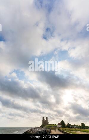 Weitwinkel Blick auf die Strandpromenade 12. Jahrhundert Zwillingstürme der ruinierten angelsächsischen Kirche und Kloster in Reculver gegen einen bewölkten Himmel. Niedriger Horizont. Stockfoto