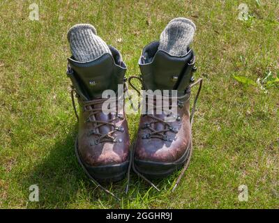 Ein Paar abgenutzte und gut gebrauchte Wanderschuhe aus Leder mit dicken Wandersocken aus Wolle Stockfoto