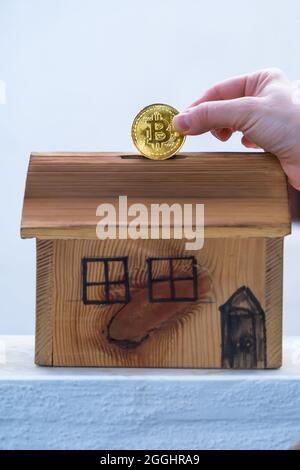 Kleines Mädchen, das ihre Bitcoin-Münze in ihrem Sparschwein zu Hause rettet. Mit virtuellem Geld in die Zukunft investieren Stockfoto