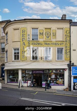 Alte verblasste gelbe Schilder für AA, Traktoren usw. an der Gebäudewand in Bath Street, Frome, Großbritannien, am 1. September 2021 Stockfoto