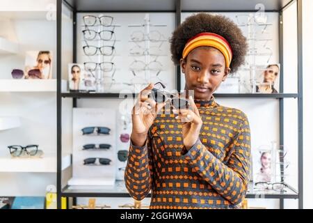 Brauchen Sie eine neue Brille.Junge Frau afroamerikanische Afro-Haare posieren mit neuen Gläsern Stockfoto