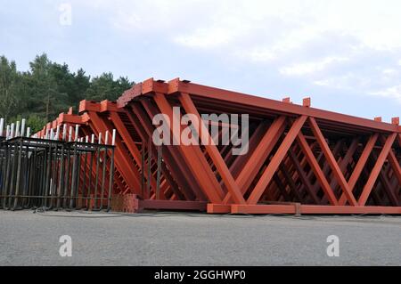 Die Stahlmetallkonstruktionen auf dem inneren Territorium des Industrieunternehmens. Lagerung von Traversen für die Installation des Dachs des Gebäudes. Stockfoto