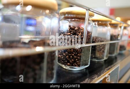 Kaffeebohnen in Glasbehältern auf einem Service-Tisch an einem Café-Kiosk. Selektiver Fokus auf eines der Gläser. Stockfoto