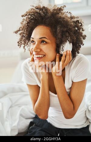 Temperamentvolle Frau mit kabellosen Kopfhörern, die ihren Lieblingslied hört Stockfoto