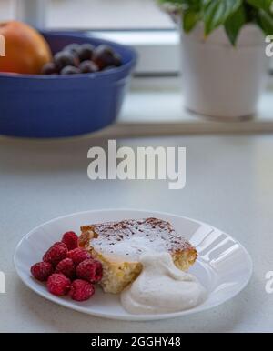 Nahaufnahme. Schwedischer Käsekuchen mit frischer Himbeere und Schlagsahne auf dem Teller Stockfoto