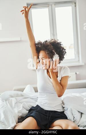 Fröhliche Dame, die morgens ihrer Lieblingsmusik lauscht Stockfoto