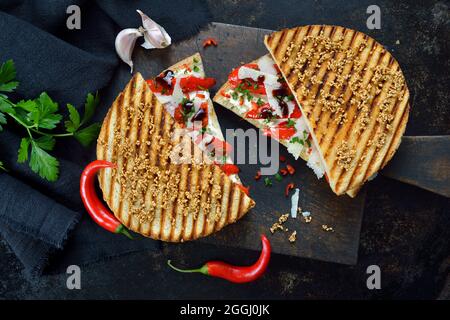 Gepresste italienische Panini mit gegrilltem Spitzpaprika, Pecorino und Frischkäse auf dunklem Hintergrund Stockfoto