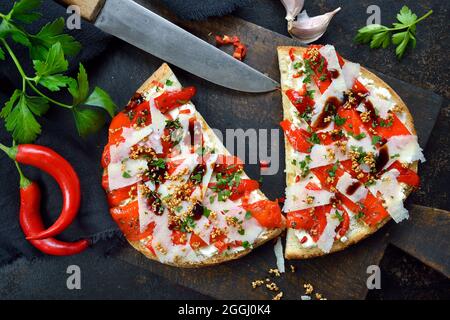 Italienische große Bruschetta mit gegrilltem Spitzpaprika, Chili, Pecorino, Sesam und Frischkäse auf dunklem Hintergrund Stockfoto