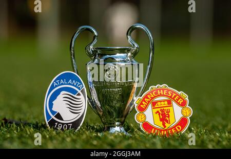 27. August 2021 Bergamo, Italien. Die Embleme der Fußballvereine Manchester United F.C. und Atalanta B.C. und des UEFA Champions League Cup auf dem Grün Stockfoto