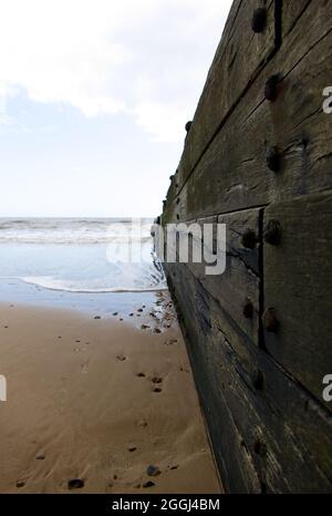 Die Flut, die entlang einer hölzernen Groyne am Strand von Frinton-on-Sea, Essex, Großbritannien, eingeht Stockfoto