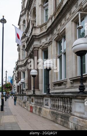 Blick nach Westen entlang Piccadilly vor der Botschaft von Japan. Japanische Nationalflagge über dem Eingangstor. Piccadilly, London, England, Großbritannien Stockfoto