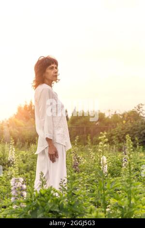 Eine Mexikanerin, die bei Sonnenuntergang ganz weiß auf dem Blumenfeld trug Stockfoto