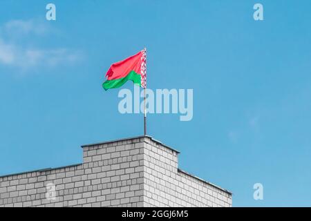 Weißrussische Flagge am Rand eines Ziegelgebäudes gegen den blauen Himmel. Stockfoto