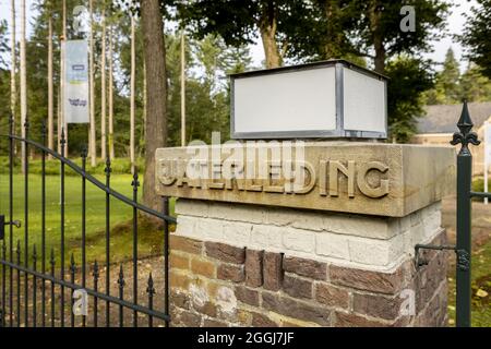 SOEST, NIEDERLANDE - 21. Aug 2021: Ziegelsäule am Eingangstor des niederländischen Frischwasserversorgungsunternehmens Vitens in grünem Wald, umgeben von Vinta Stockfoto