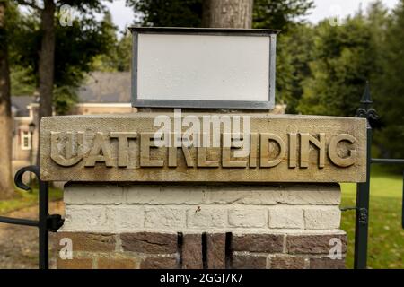 SOEST, NIEDERLANDE - 21. Aug 2021: Vintage-Wort auf Ziegelsäule am Eingangstor des niederländischen Frischwasserversorgungsunternehmens Vitens in grüner Waldumgebung Stockfoto