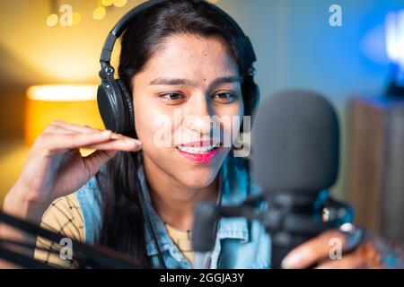 Nahaufnahme Kopf Aufnahme von glücklich fröhlichen jungen Mädchen Podcasting von der Kamera suchen - Konzept der Frau Bloggerin oder DJ arbeiten auf Rundfunk-Studio. Stockfoto