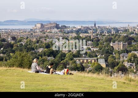 Ein Paar, das ein Picknick auf Blackford Hill, Edinburgh mit Blick auf die Skyline von Edinburgh, Blackford Hill, Edinburgh Schottland Großbritannien macht Stockfoto