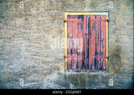 Verwitterte Fassade eines verlassenen Gebäudes mit Fenster und geschlossenen Fensterläden Stockfoto