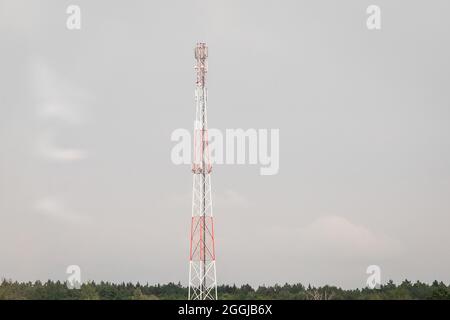 Kommunikationsturm von mobilen und mobilen Geräten mit Antennen auf dem Hintergrund eines grauen Himmels. Stockfoto