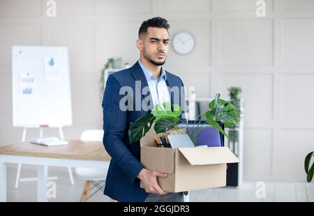 Konzept der Wirtschaftskrise. Unglücklicher arabischer Mann, der persönliche Sachen hielt, nachdem er im Büro gefeuert wurde Stockfoto