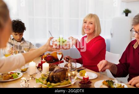 Liebevolle Familie mit mehreren Generationen, die gemeinsam Thanksgiving oder Weihnachtsessen zu sich nimmt und zu Hause leckeres festliches Essen genießt Stockfoto