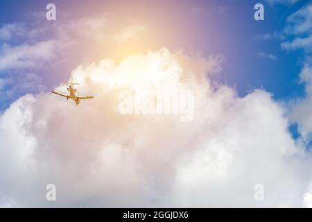 Kleines weißes Flugzeug, das über den Wolken und der Sonne fliegt Stockfoto