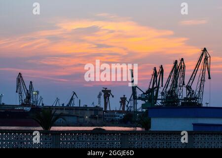 Hafenkrane bei Sonnenuntergang in Varna. Stockfoto