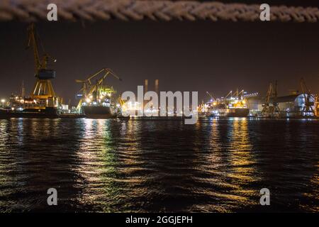 Kräne und Frachtschiffe im Hafen von Constanta, Rumänien, während der Nacht. Stockfoto