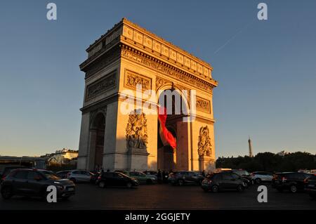 Die späte Nachmittagssonne beleuchtet den Triumphbogen, während der Verkehr um das Denkmal auf dem Place Charles de Gaulle in Paris fließt. Stockfoto