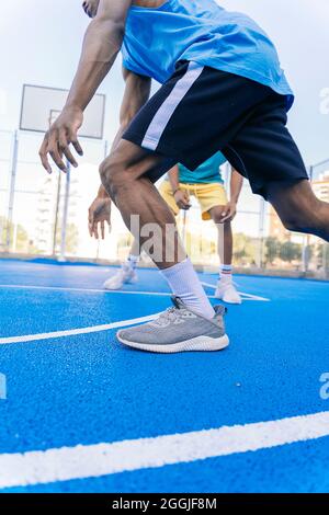 Nahaufnahme der Beine junger sportlicher afroamerikanischer Männer, die tagsüber Street-Basketball spielen Stockfoto