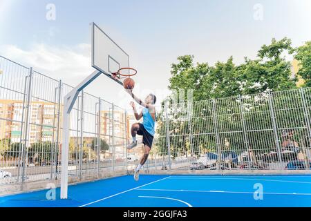 Unbekannter afrikanischer Junge in Sportkleidung Basketball spielen und den Ball werfen. Stockfoto