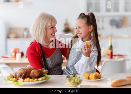 Familienküche. Glückliche Großmutter umarmt niedliches Mädchen, die traditionelle Thanksgiving oder Weihnachtsessen in der Küche Stockfoto