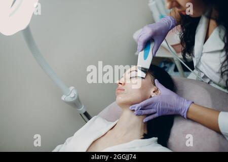 Frau, die Reinigungstherapie mit einem professionellen Ultraschallgerät in Kosmetikbehandlungen erhält. Stockfoto