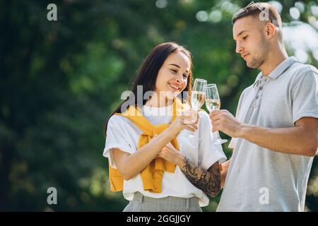 Junge schöne Paar mit Picknick und klirrende Gläser Champagner an hellen Sommertag Stockfoto
