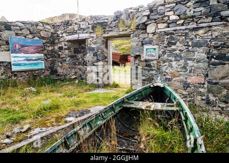 Ein altes, ruiniertes und dachloses Gebäude mit alten Booten bildet eine ungewöhnliche Kunstgalerie in der Skerray Bay an der Nordküste Schottlands direkt vor der NC500. Stockfoto