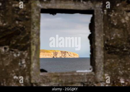 Skerray Bay an der Nordküste Schottlands direkt an der NC500. Eilean Nan Ron wird durch ein glasloses Fenster in einer alten Wand gesehen. Stockfoto