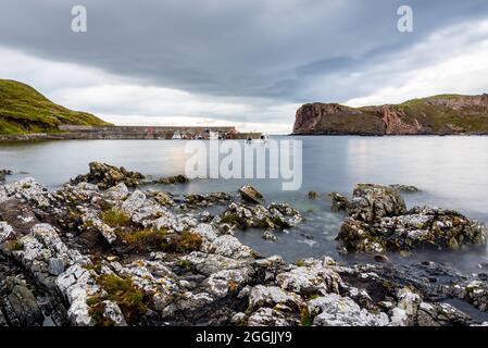 Ein ruhiges, langbelichttes Bild von Skerray Bay, Schottland, an einem bewölkten Tag, einschließlich der kleinen Hafenmauer und Neave oder Coomb Island auf der rechten Seite. Stockfoto