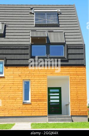 Modernes Haus mit Energieeinsparung und Energieeffizienz. Öko-Haus mit Dachfenster, Isolierung, Sonnenkollektoren und Solar-Warmwasserbereiter (SWH)-System. Stockfoto