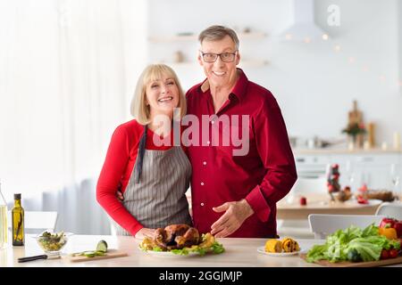 Fröhliches Senior-Paar posiert, Kochen truthahn für Weihnachten oder Thanksgiving-Abendessen, Vorbereitung Weihnachtsessen in der Küche Stockfoto
