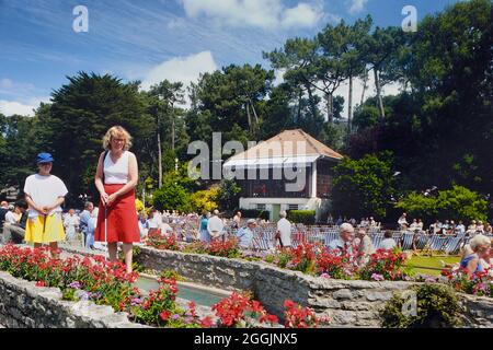 Spieler auf dem Minigolfplatz und ein Publikum, das einem Konzert im Pine Walk Bandstand, Lower Gardens, Bournemouth, Dorset, England, zuhört, VEREINIGTES KÖNIGREICH. Ca. 1980 Stockfoto