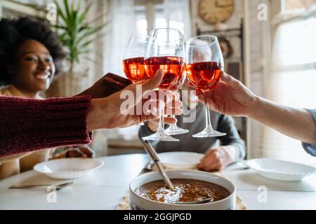 Fröhliche, multiethnische Menschen, die zu Hause zusammen toasten und Spaß haben Stockfoto