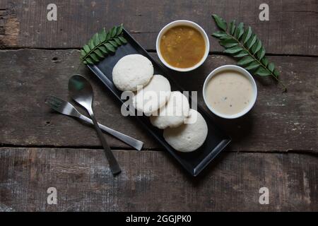 Südindische Snacks idli sambar oder Idly sambhar, zubereitet durch Dämpfen fermentierten Reis und serviert mit Kokosnuss-Dip und Gemüsesuppe. Draufsicht Stockfoto