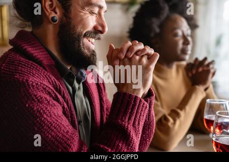 Junge, multiethnische Paare beten zum Herrn, um ihr Essen und ihren Tag zu segnen Stockfoto