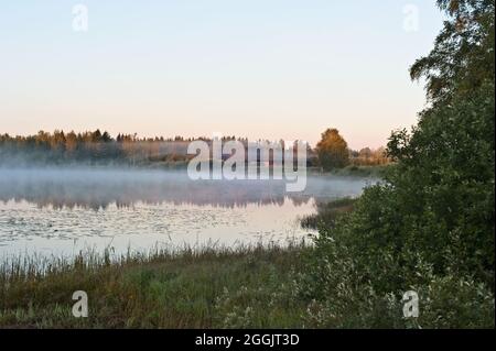 Flussszenen zwischen Wäldern und Nebel an einem bunten Herbstmorgen. Stockfoto