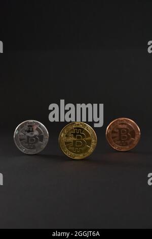 Goldene, Bronze und Silber Bitcoin Münzen BTC Währung zentriert und auf dunklem Hintergrund ausgerichtet Stockfoto